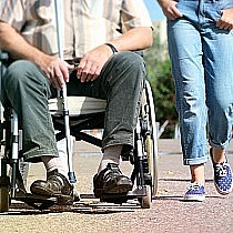 zdjęcie ilustracyjne - od lewej osoba na wózku inwalidzkim, osoba idąca